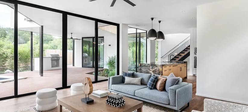 Large modern picture window with a black aluminum frame bringing daylight and a wide outdoor view into a living room
